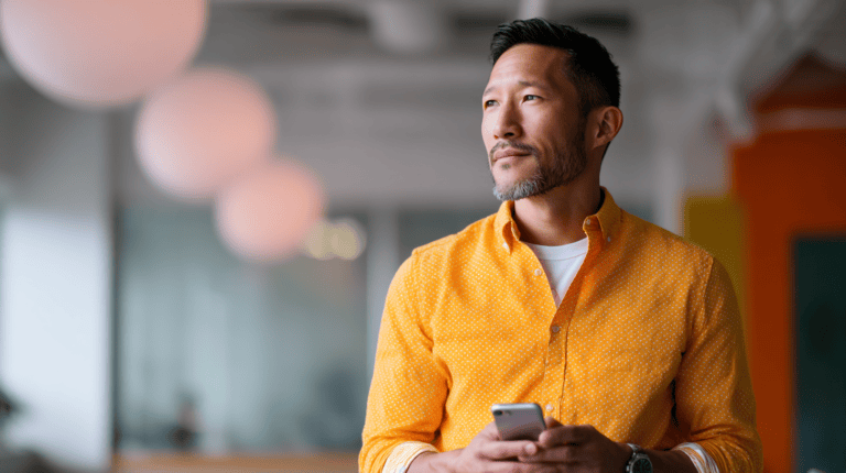 Man in orange shirt using smartphone.