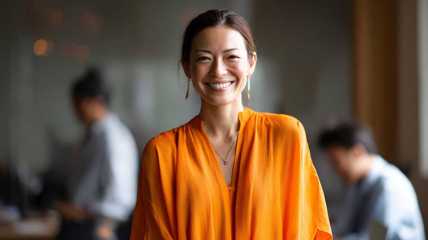 Woman in orange blouse, office background.