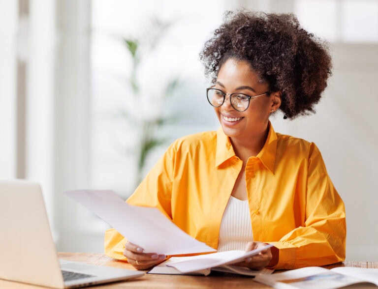 a woman in a yellow shirt reading a paper