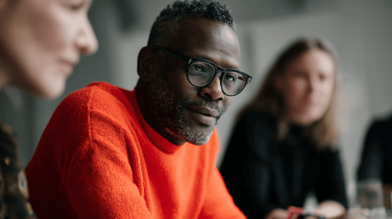 Man in orange sweater, focused expression.