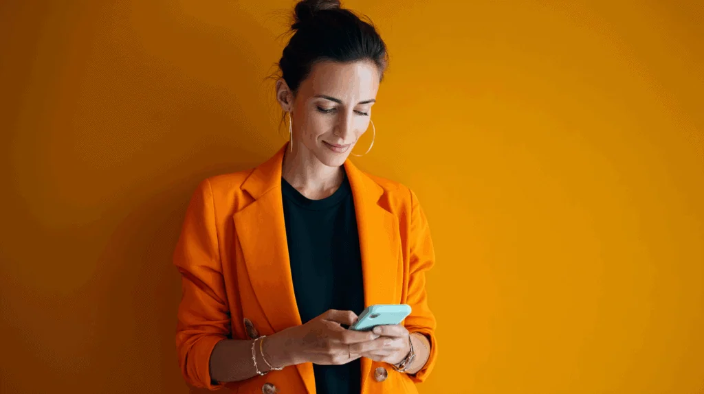 a woman in orange jacket looking at a phone