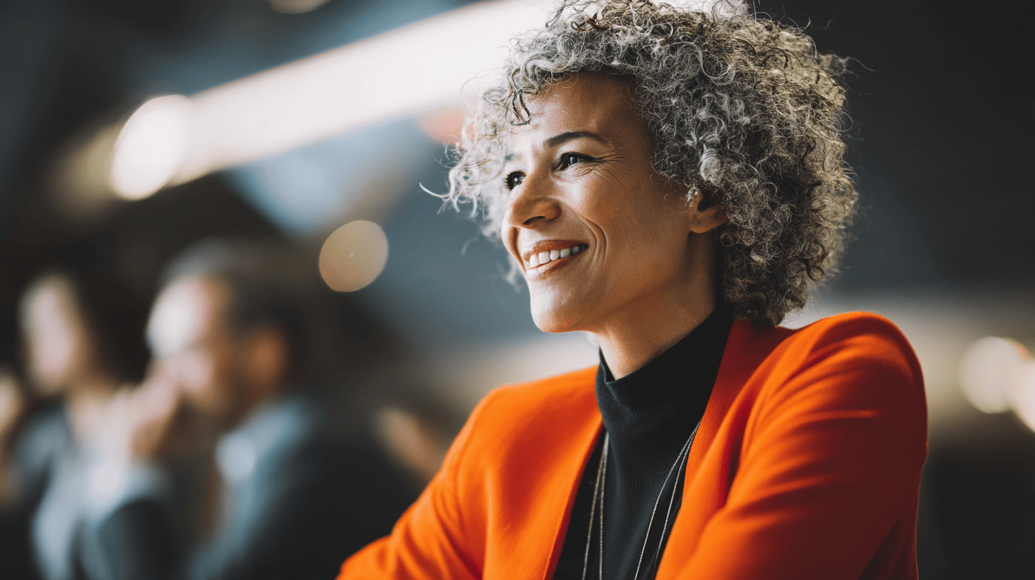 Smiling woman in vibrant orange blazer.