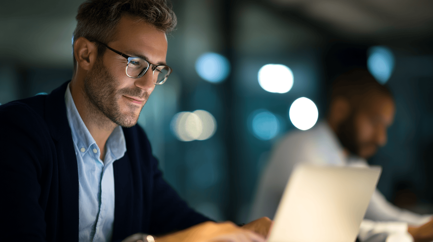 Man working on laptop in dim light.