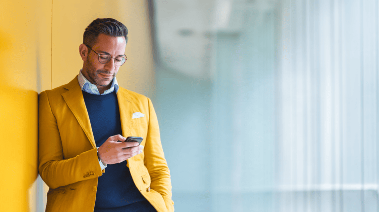 Man in yellow jacket using smartphone.