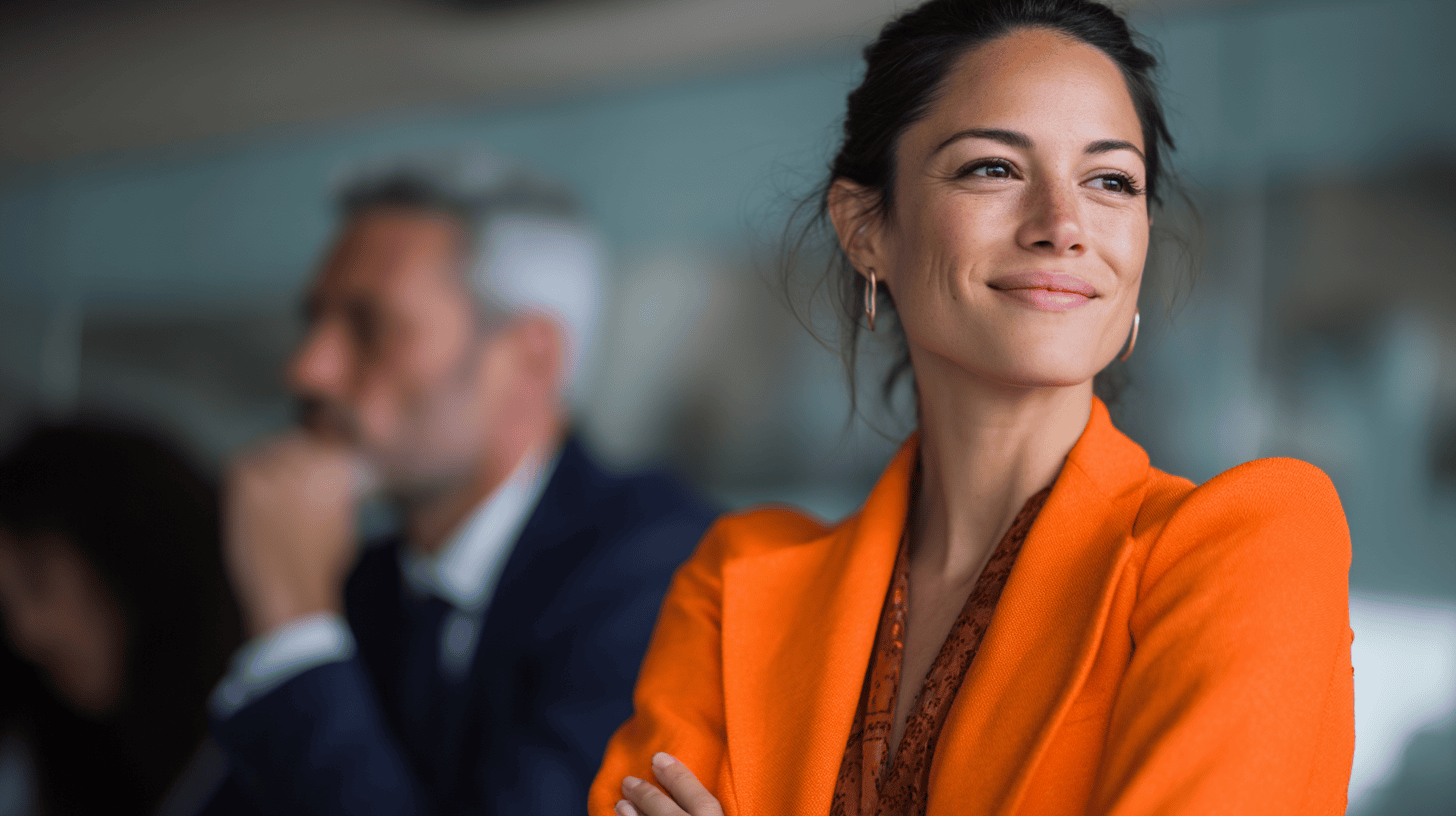 A woman in an orange blazer smiles confidently while a man in the background appears deep in thought.