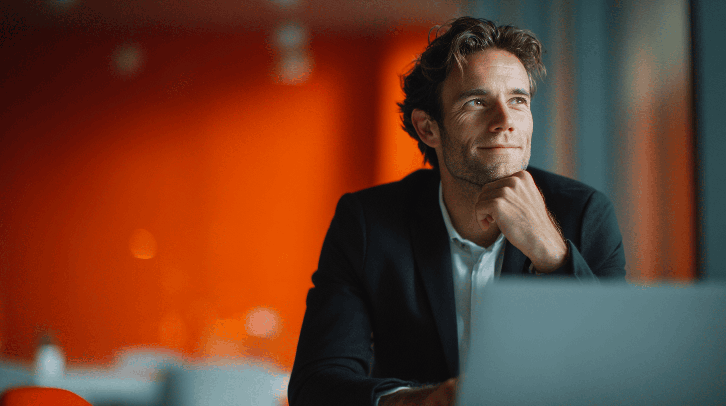 A thoughtful man in a suit sits at a table, looking upward, with a blurred orange background.