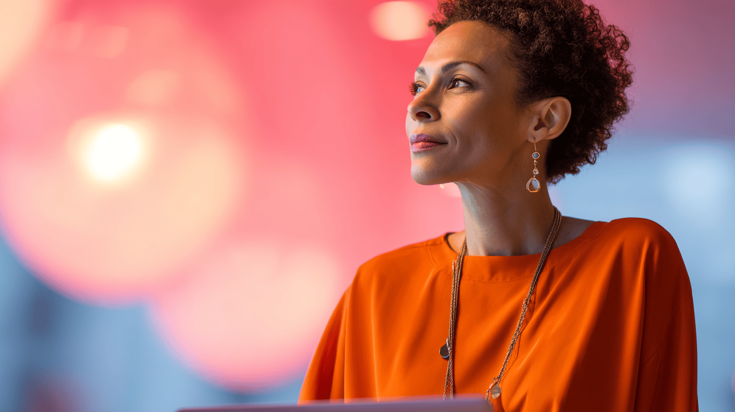 A woman with curly hair wearing an orange top and earrings gazes thoughtfully, with blurred colorful lights in the background.
